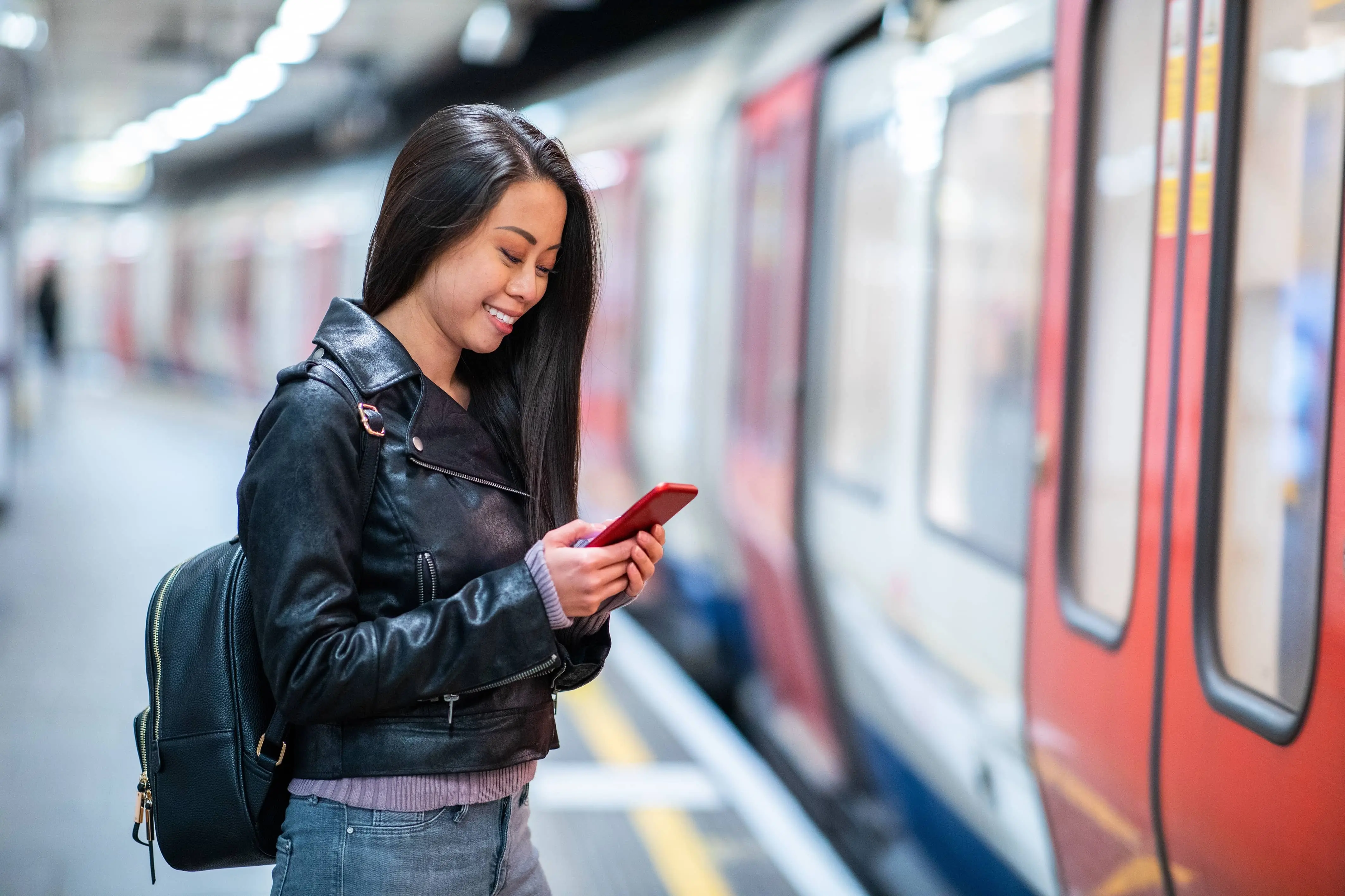 Underground Trains: A woman looks at her phone whilst waiting to board an Underground train.