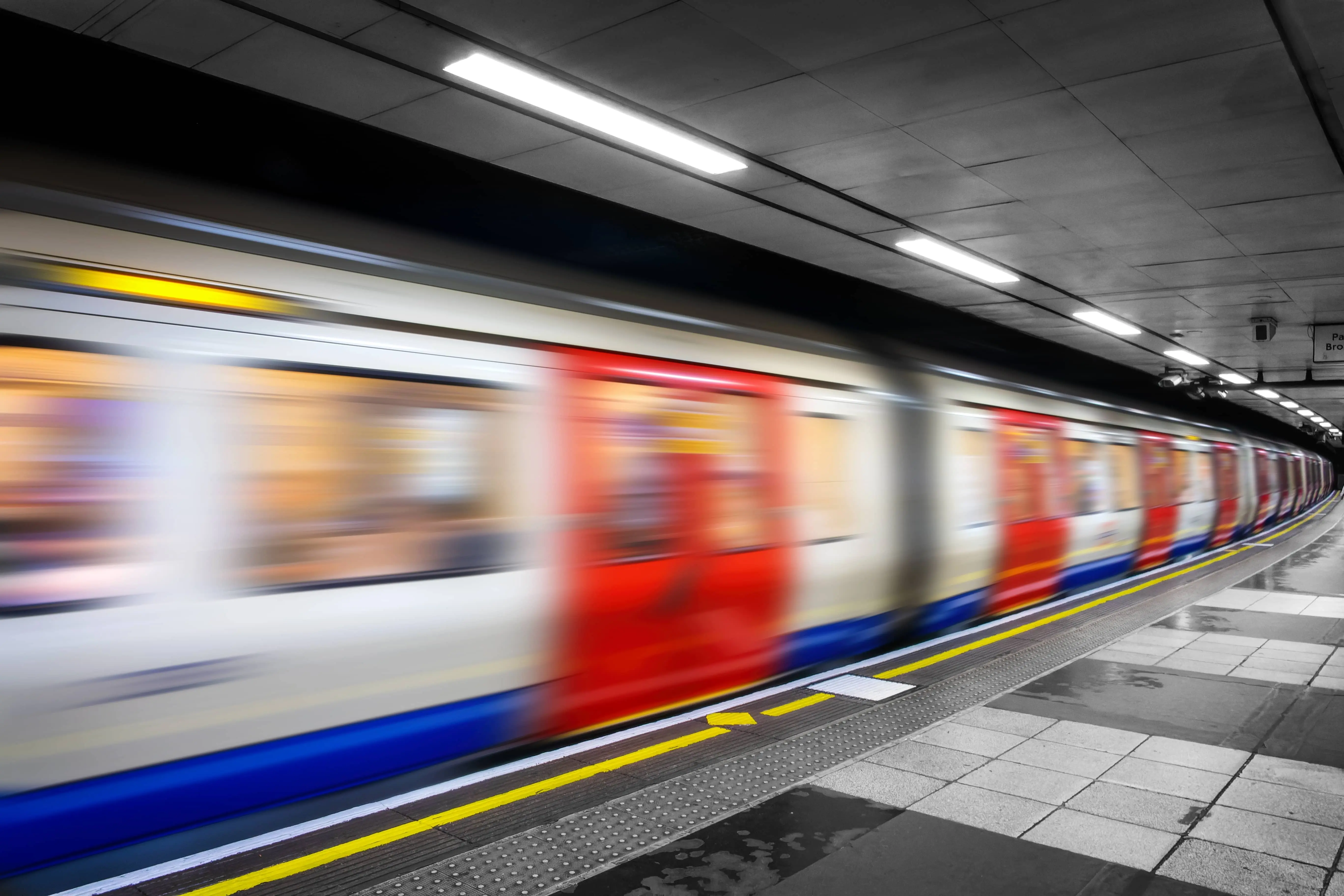 View of a London Underground platform with a train in motion.