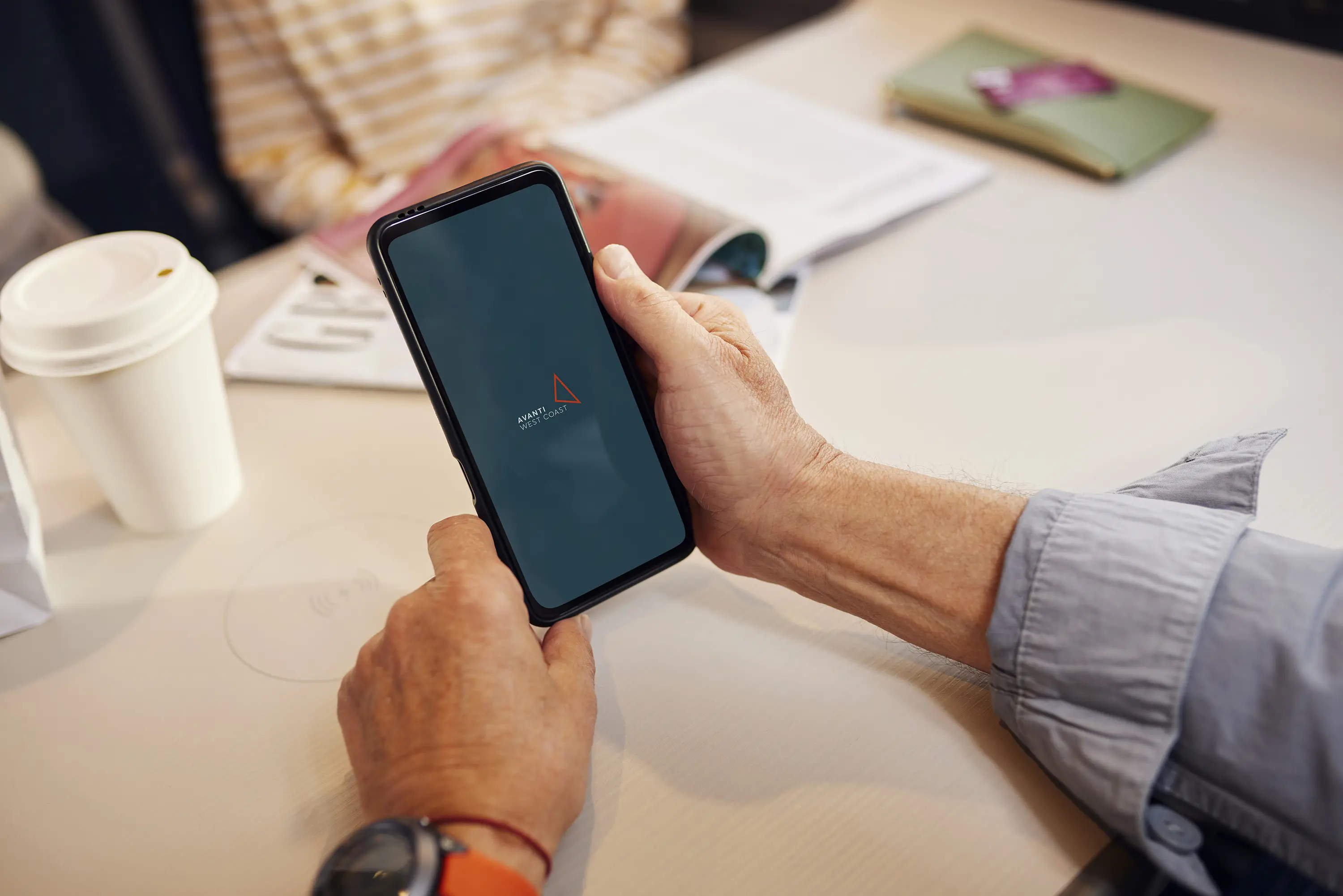 Close up of a man holding a phone with the Avanti app open on the screen