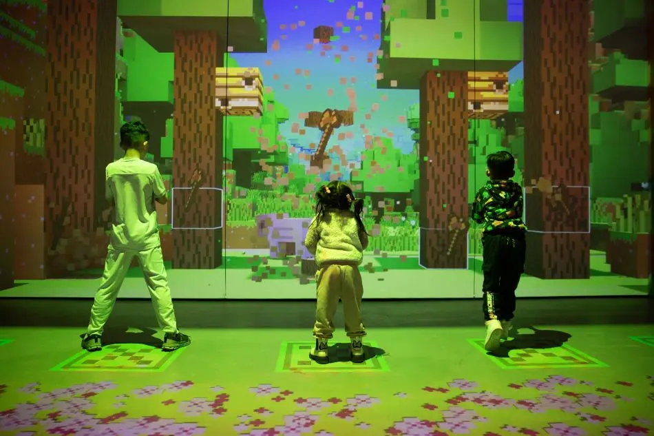 The backs of three kids playing a game at the Minecraft Experience