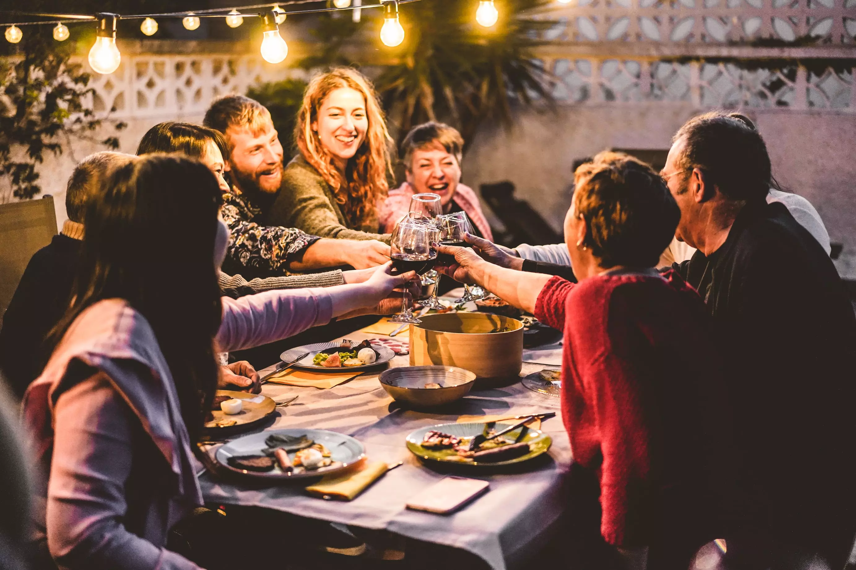 A group of friends cheers their glasses across a table at a restaurant in the evening.