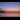 A longshot of Folkestone's Sunny Sands Beach at sunset, with an orangey-blue sky and lots of birds on the sand.