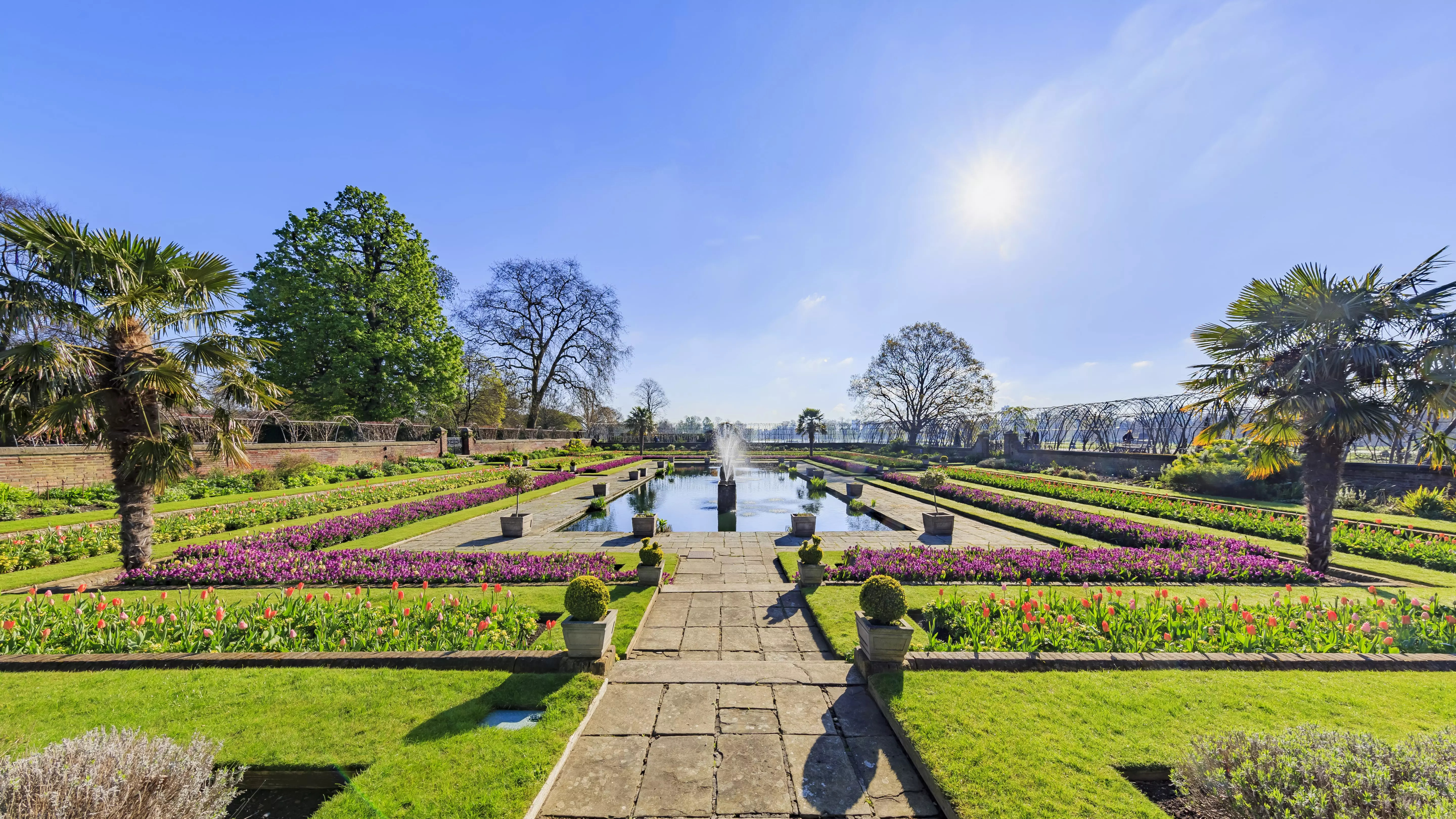 A stunning shot of the fountain, water feature, trees, and flowers at Hyde Park.