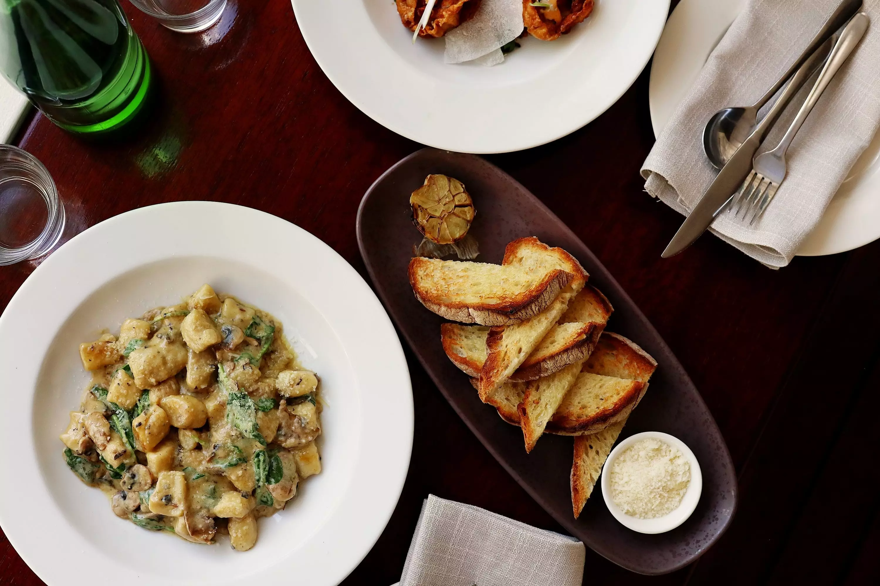 A table of garlic bread, gnocchi and wine at a restaurant.