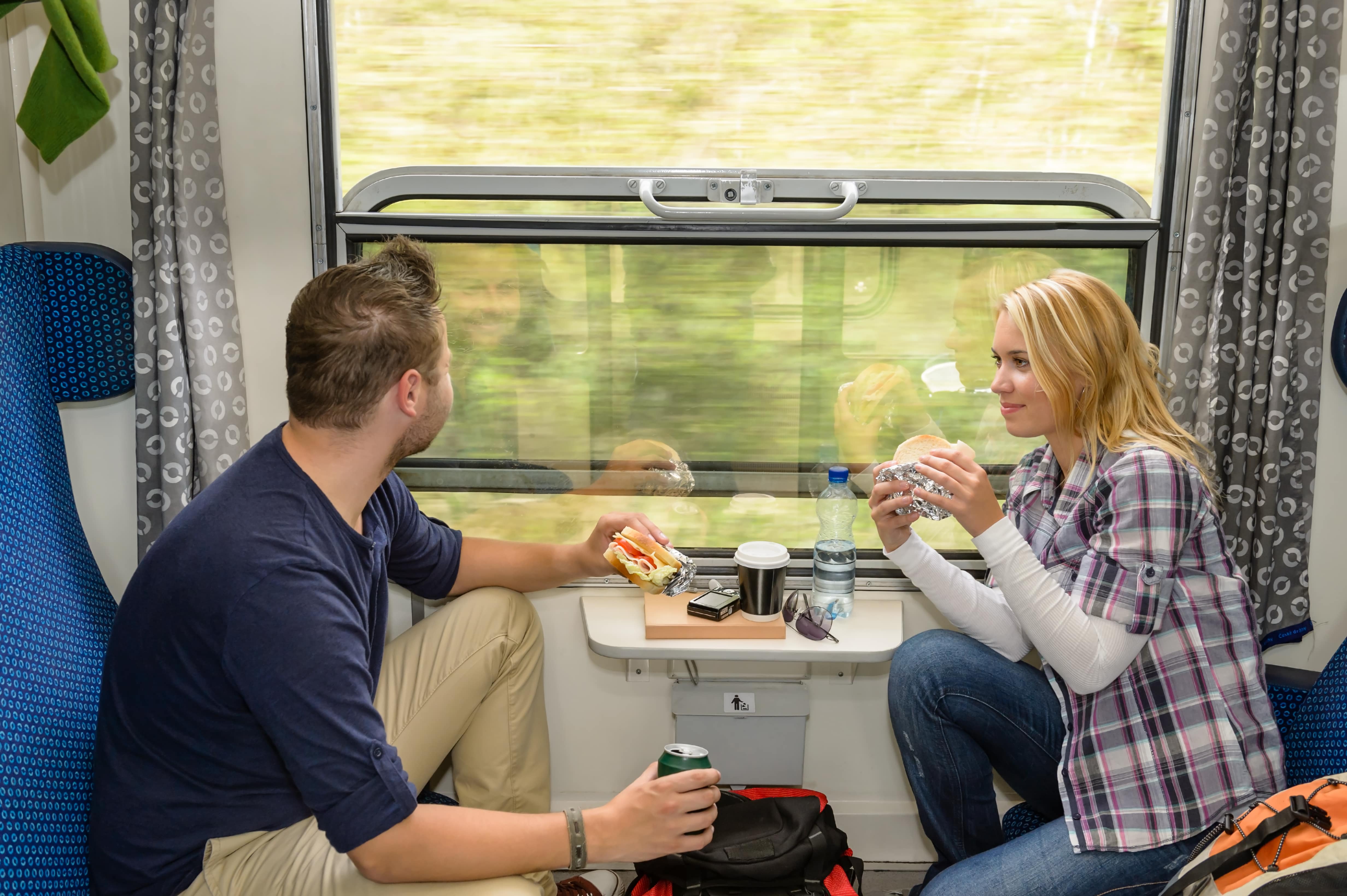 Food on Trains: A young couple share sandwiches on a train as the scenery flashes by