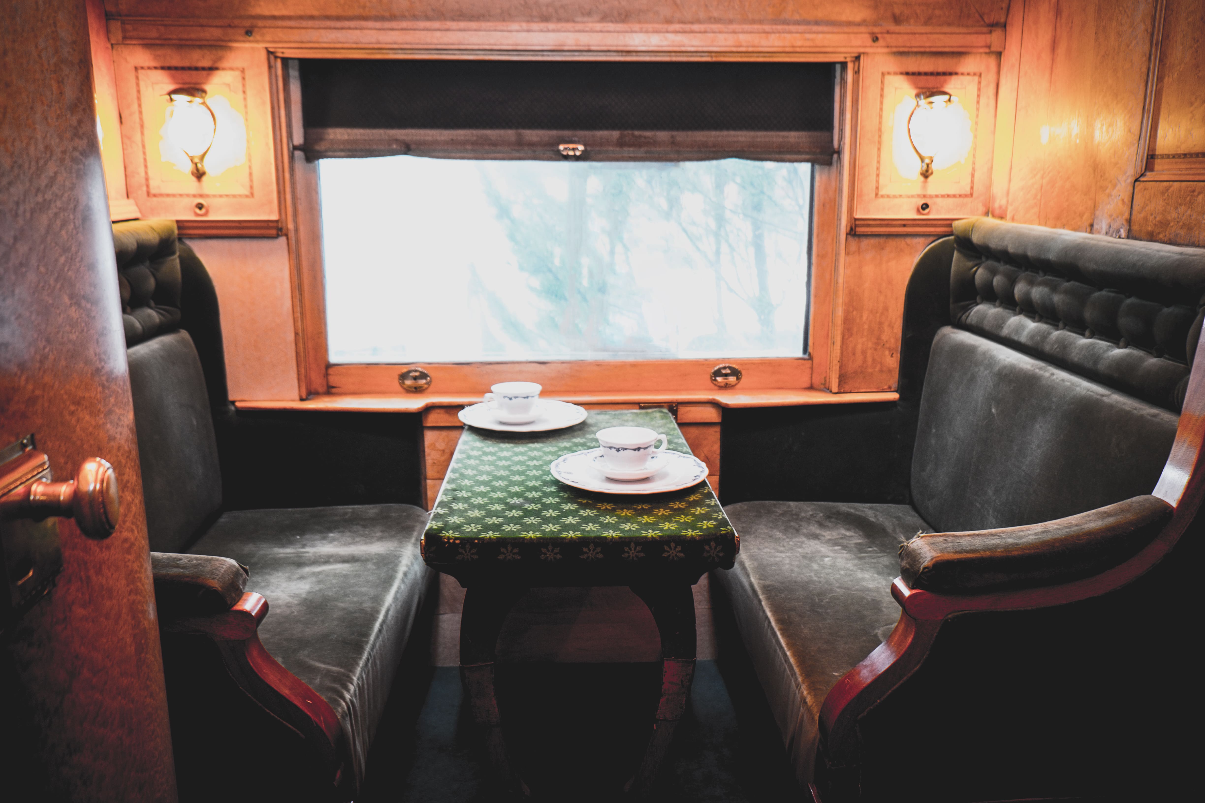 Train Carriages: A vintage train compartment with plush seating, cups of tea and warm ambient light