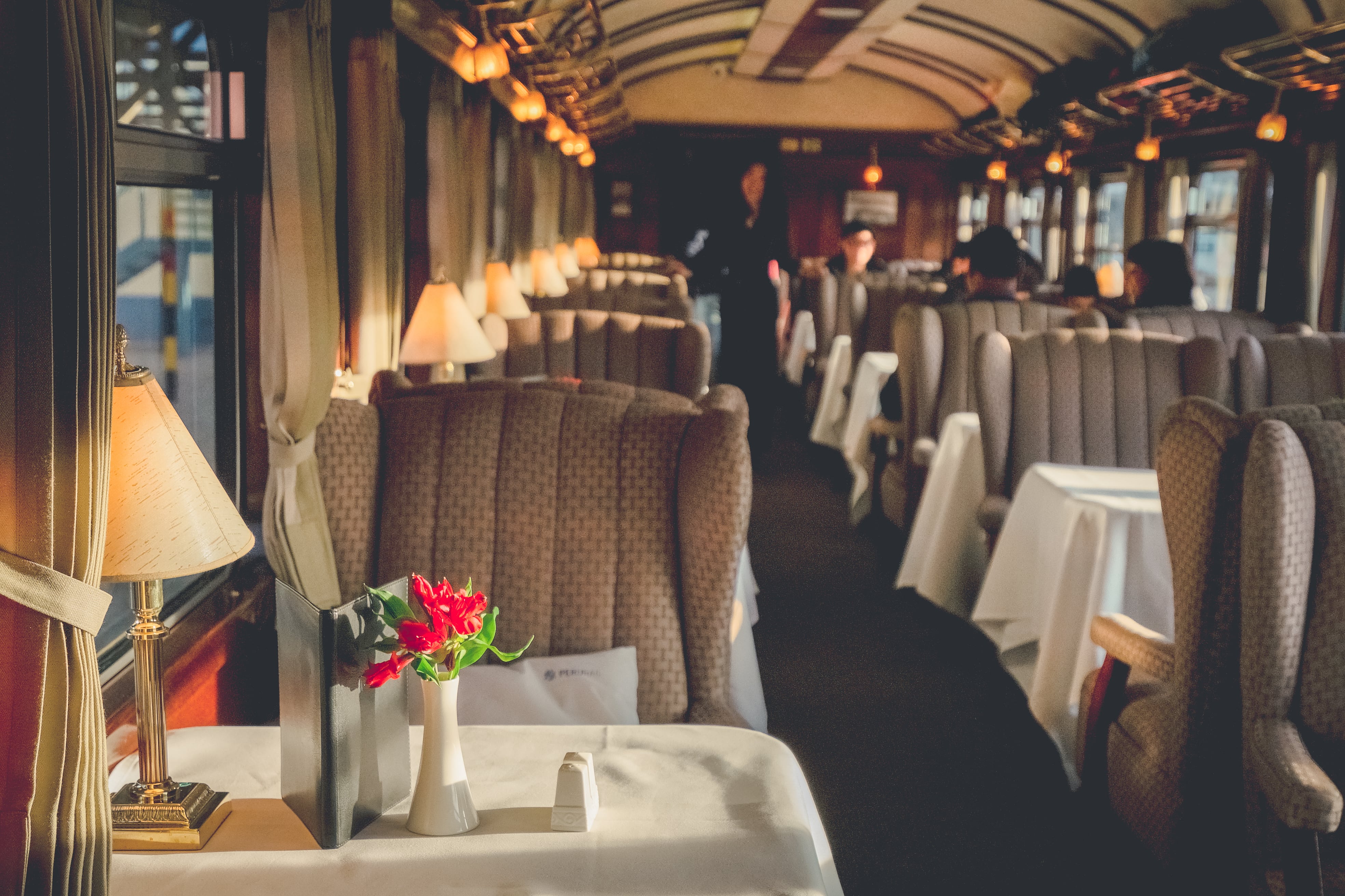 Train Carriages: Elegant vintage train dining car with plush seating, table lamps, and white tablecloths