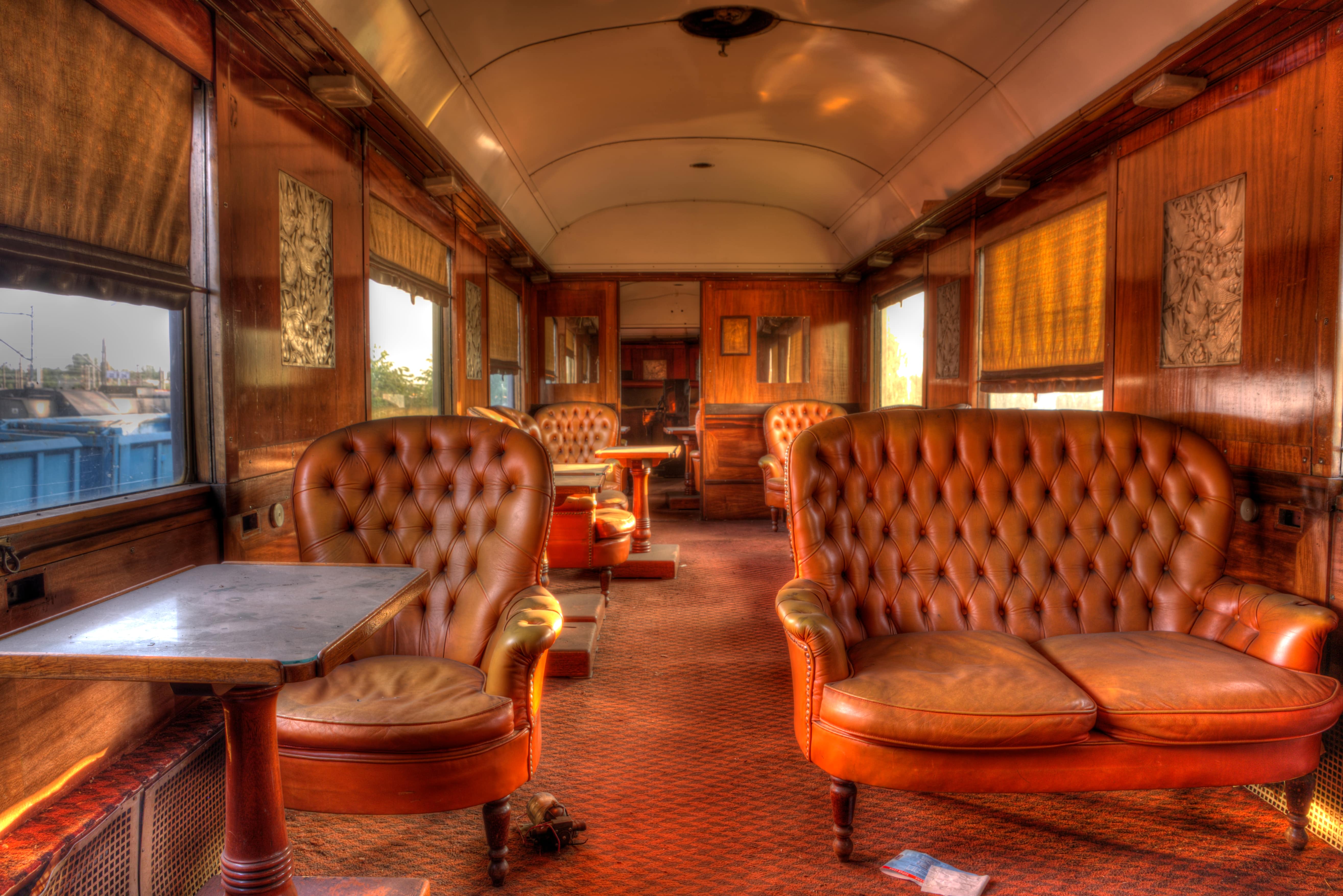 Rail Advertising: A vintage train carriage interior with luxurious tufted leather seating, wooden panelling, and warm lighting