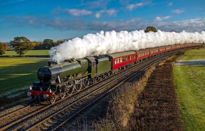 A steam locomotive passing through the countryside with a full head of steam