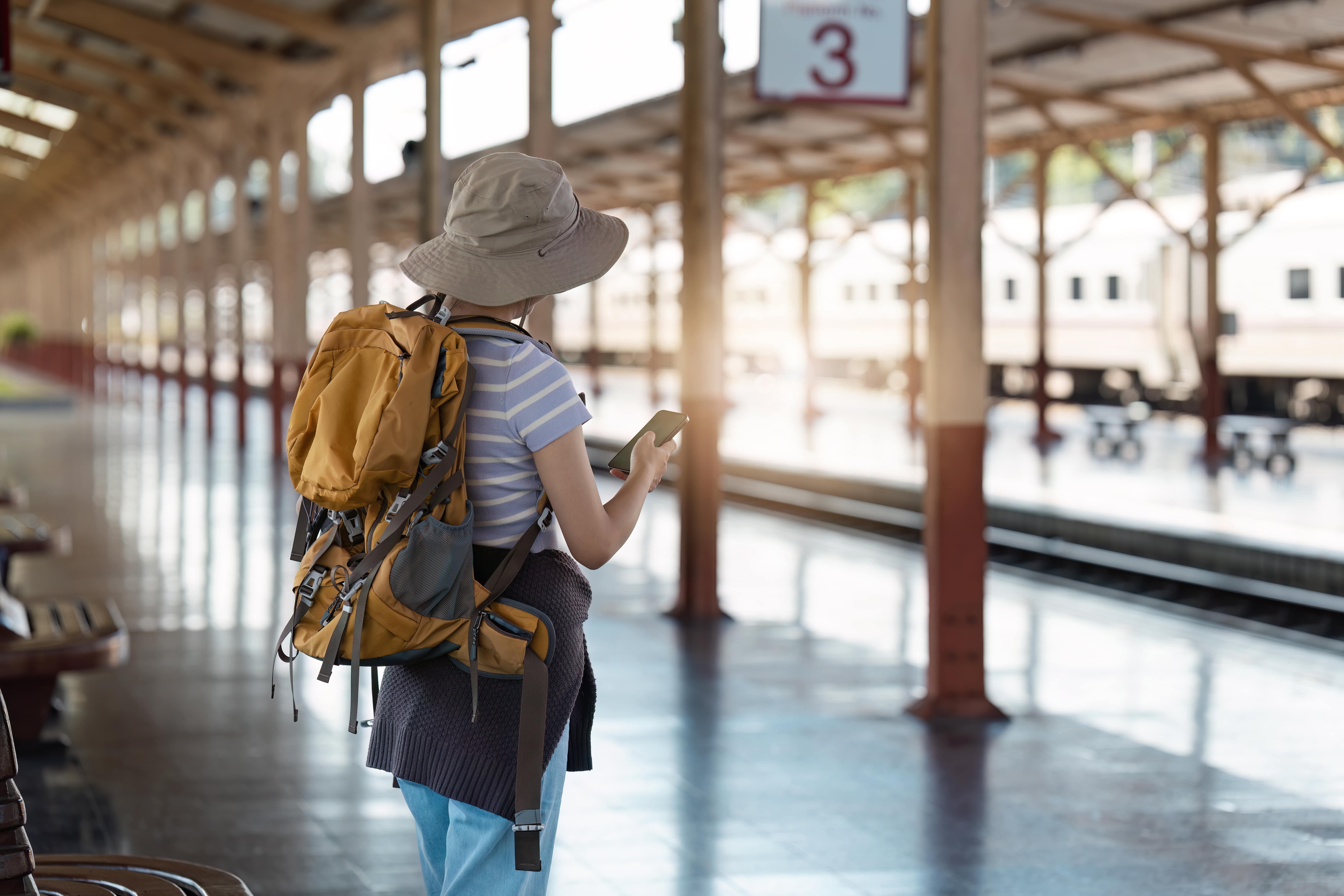 West Coast Train Line: A women wearing a hat and backpack standing at the station.