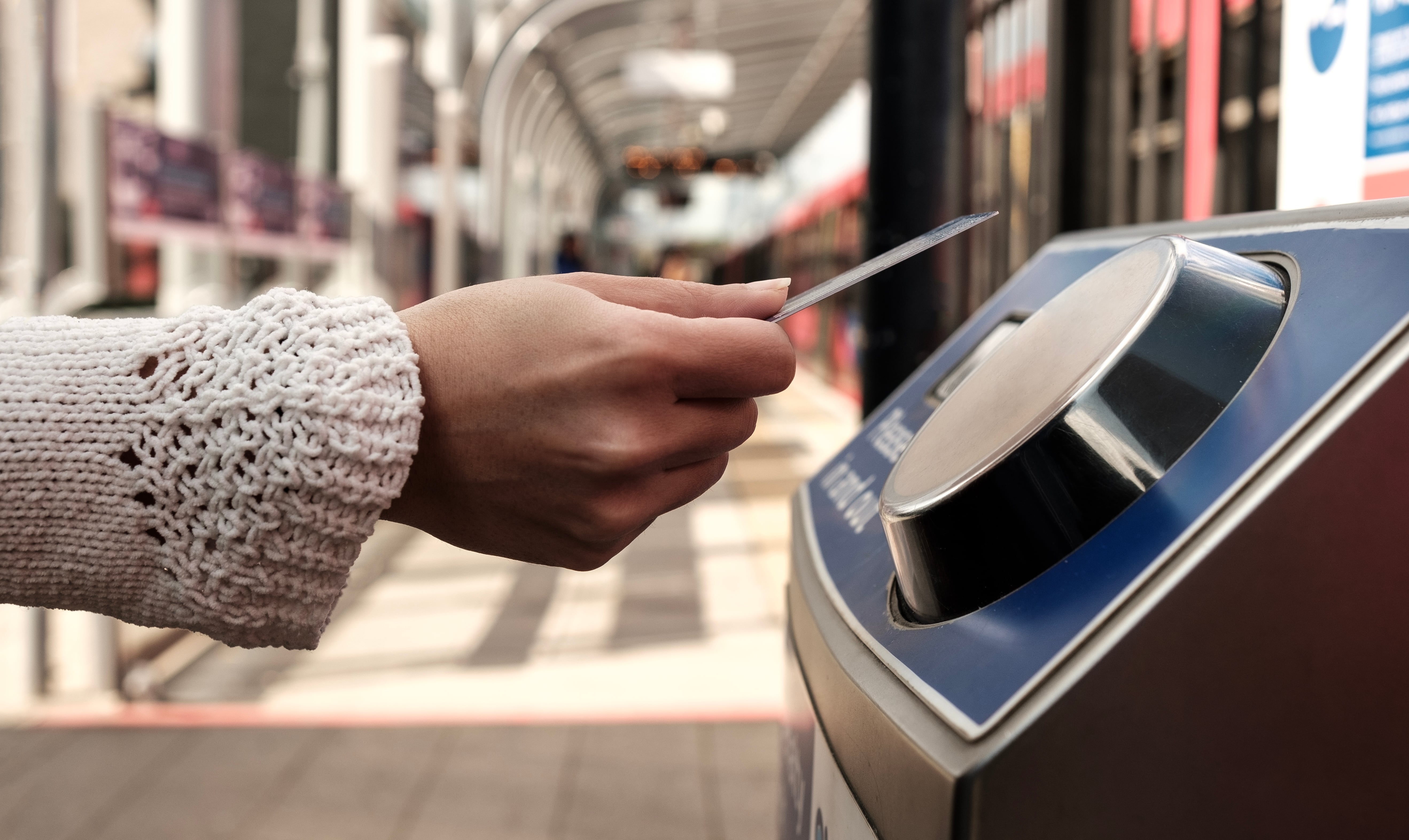 Train Ticket Design: Close-up of a person scanning a travel card at a train station tap machine