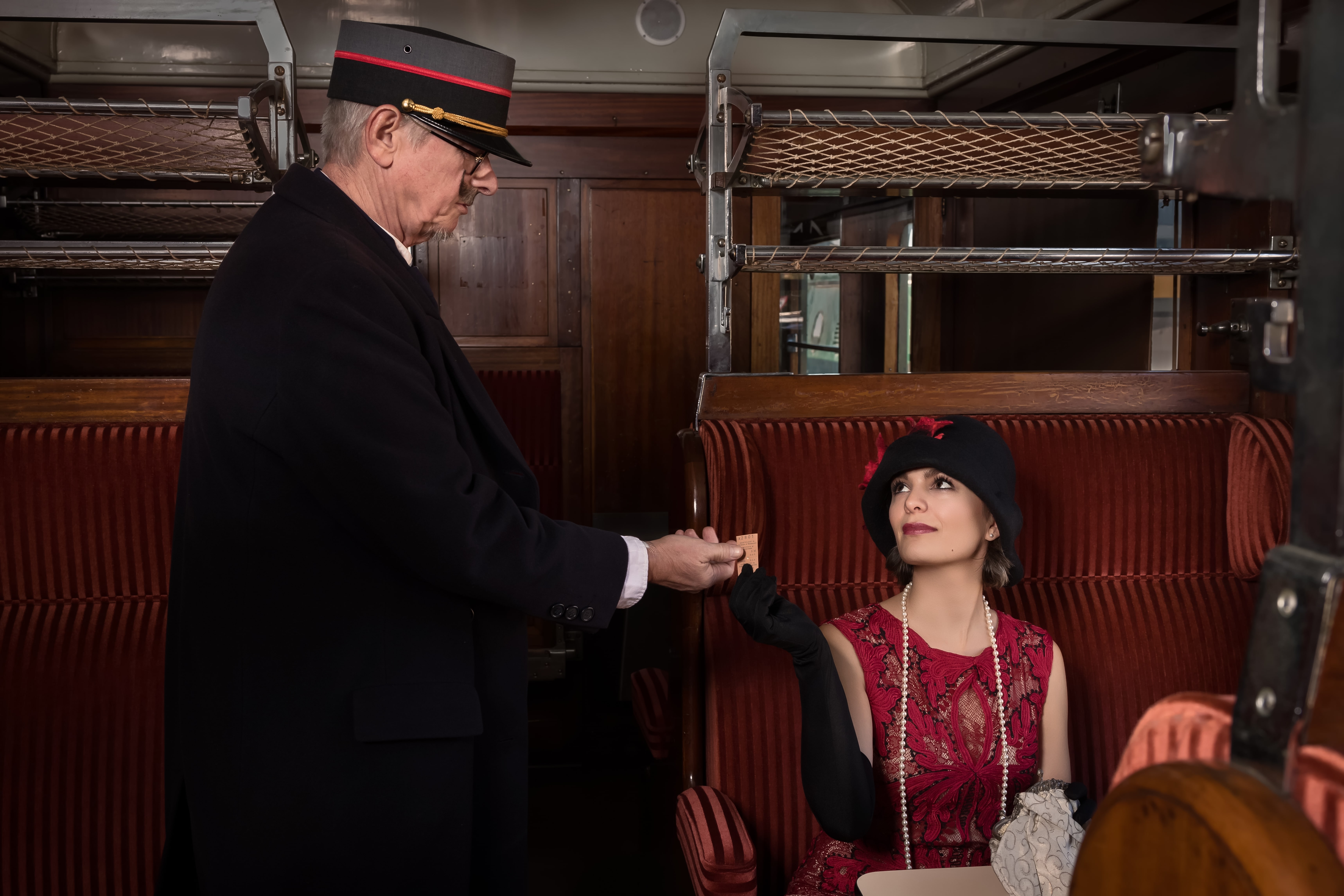 Train Classes: A reenactment of a steam train conductor taking a ticket in a 1927 authentic first class train interior.
