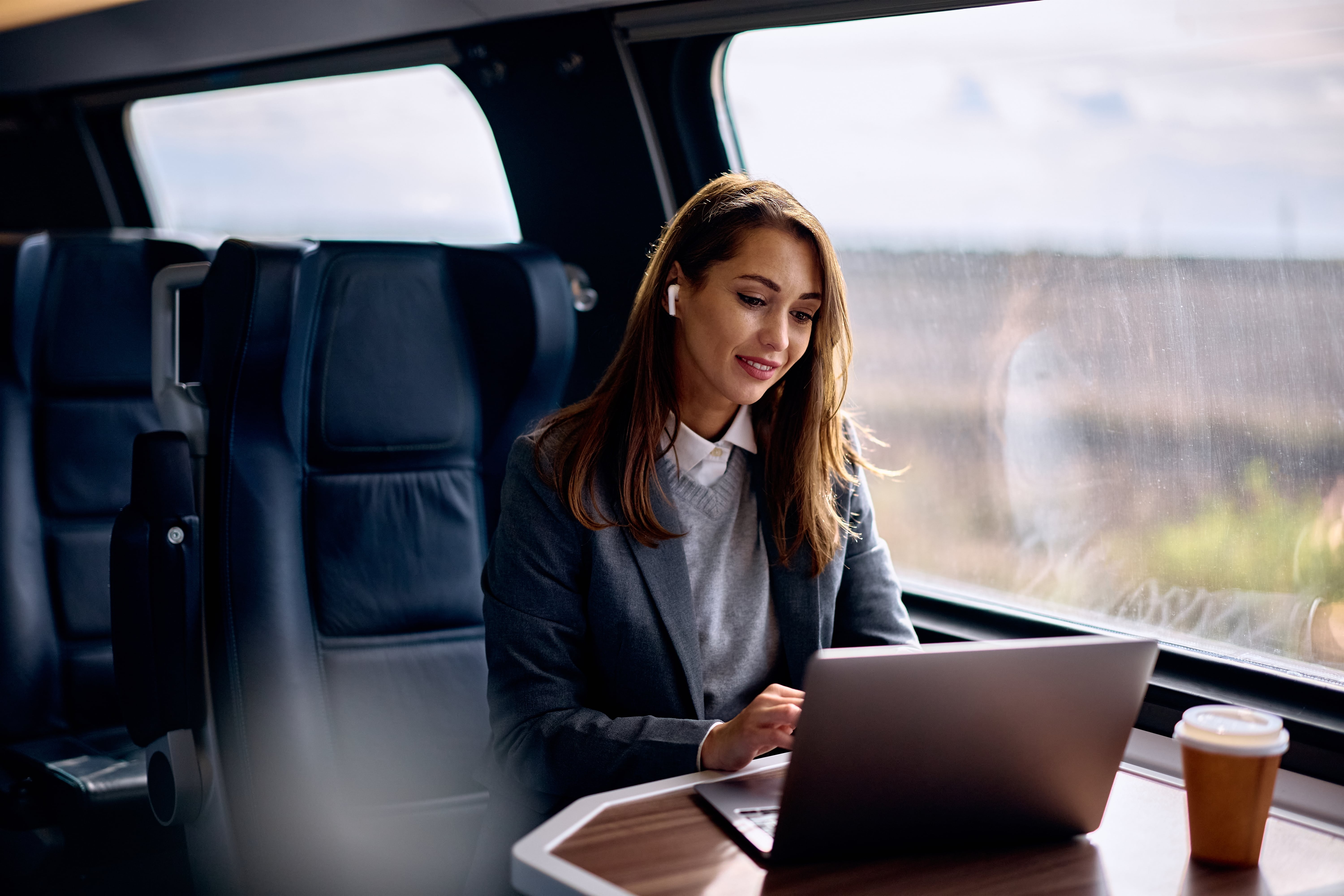 Train Classes: A businesswoman working on her laptop in a modern train carriage.