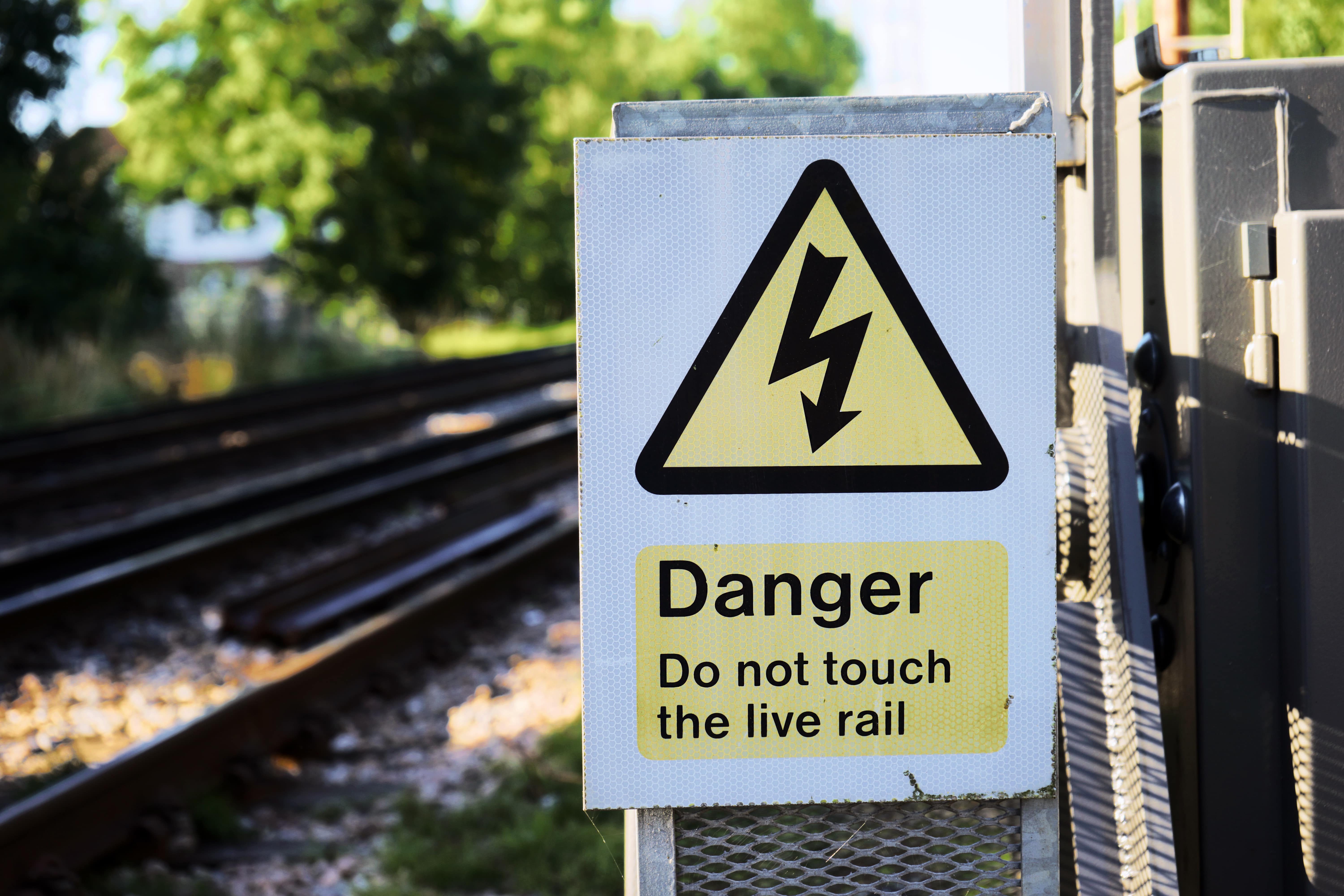 Rail Safety: A yellow ‘Danger’ sign warning of electricity on rail tracks.