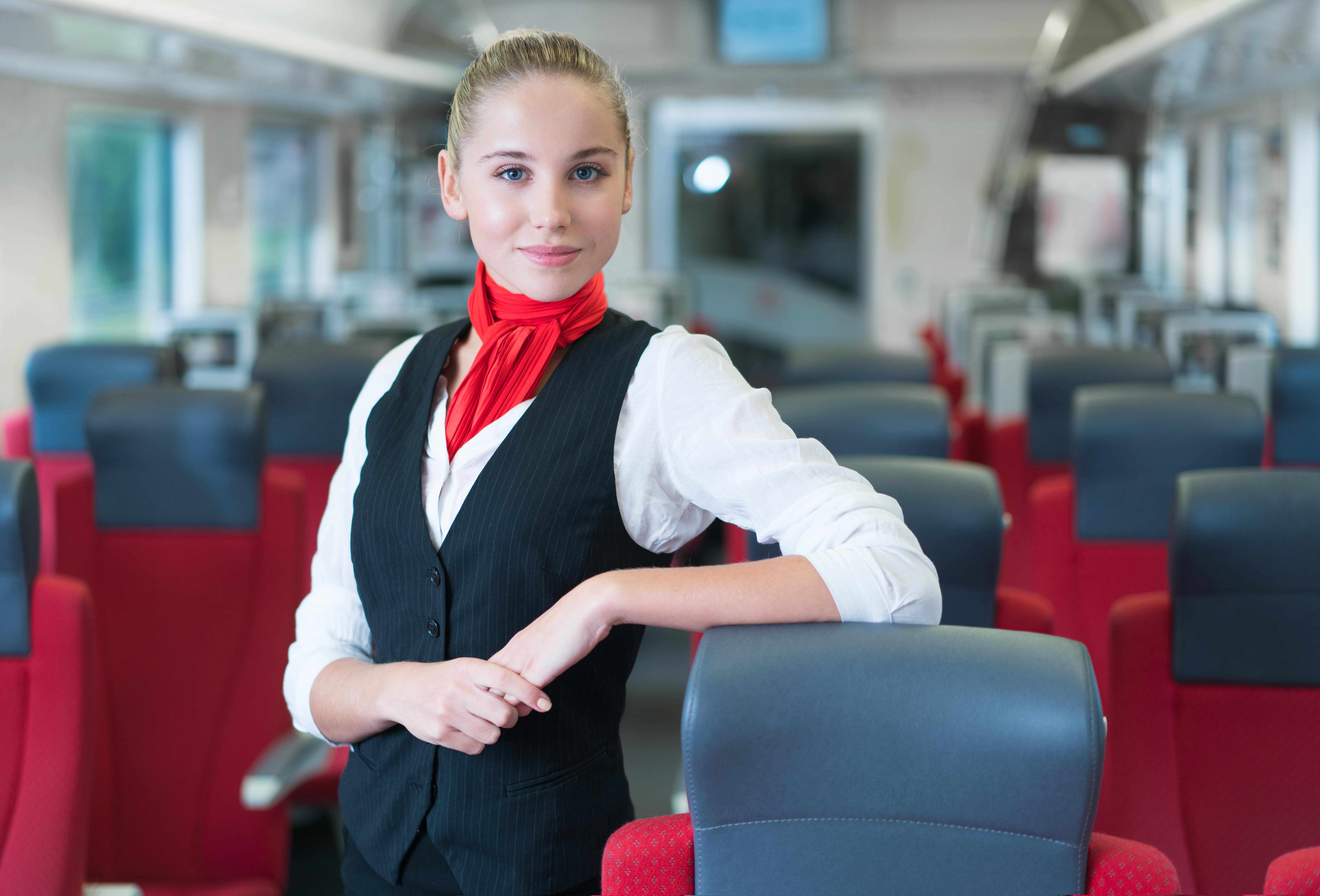 Women in Rail: we see the back of a female engineer wearing a hard hat as she looks at a train in the background.