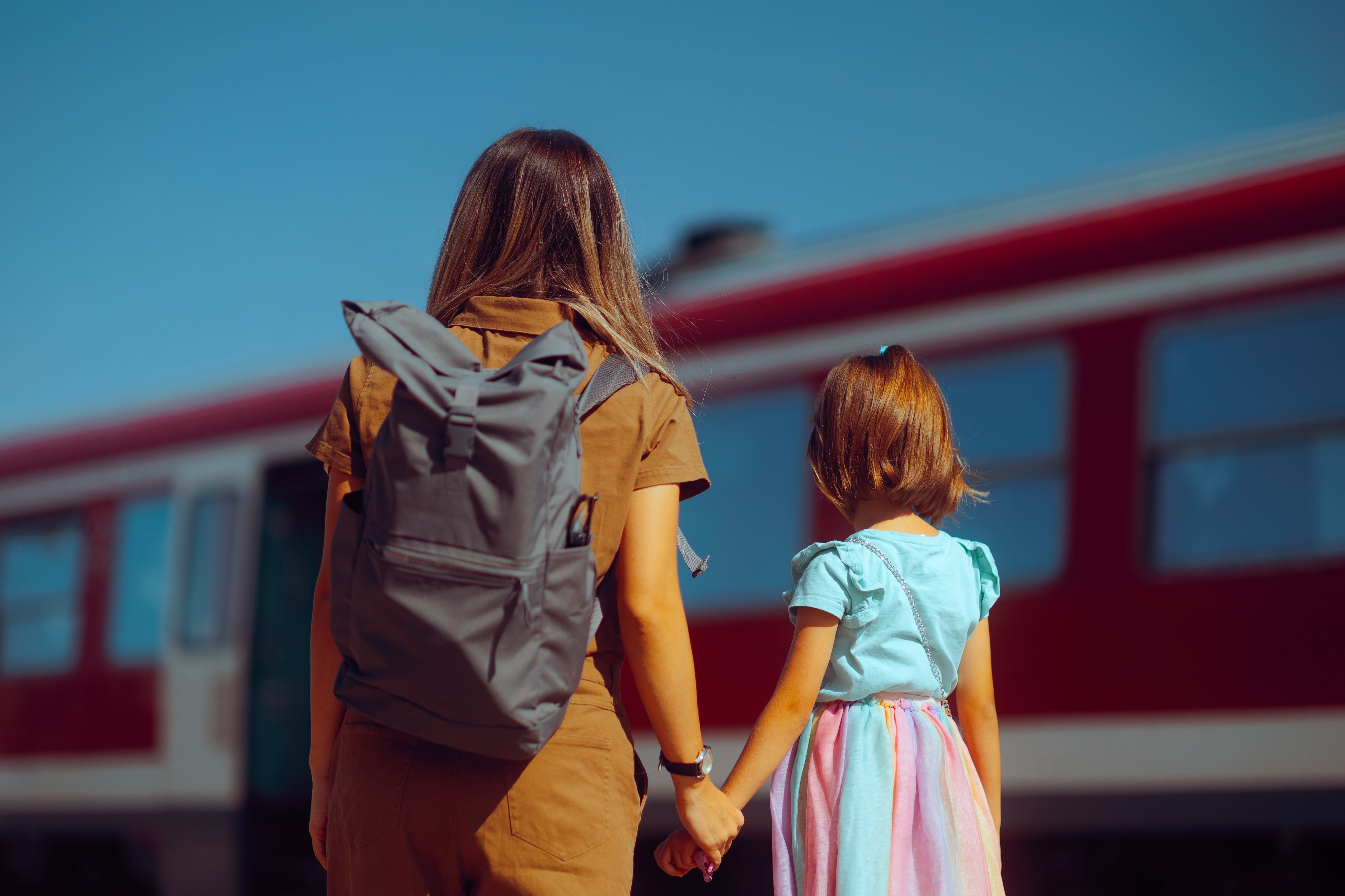 Bicentennial: Mother and daughter holding hands at a train station, preparing to board a red train
