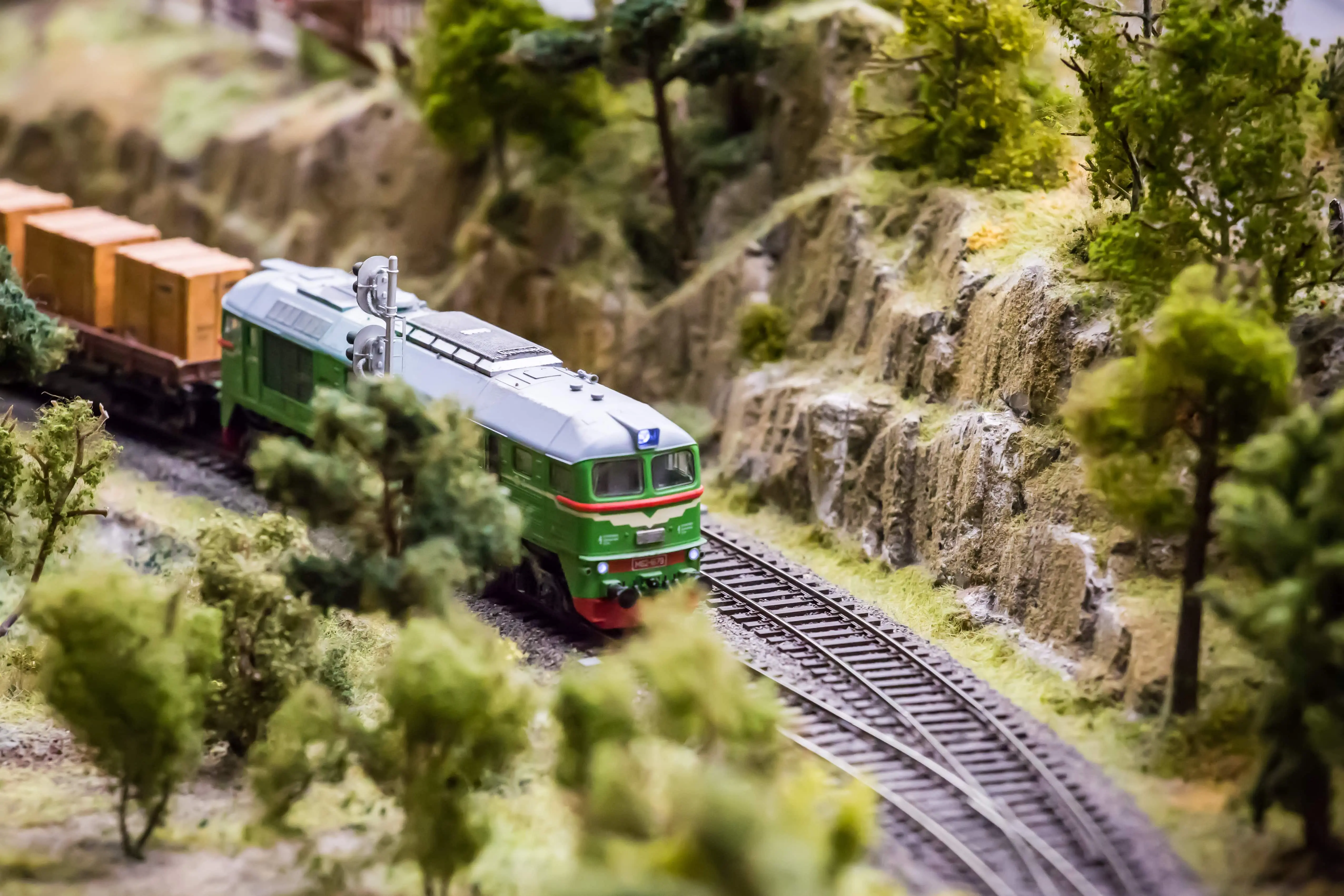 Model Trains: A model railway depicting a green train passing by small trees.