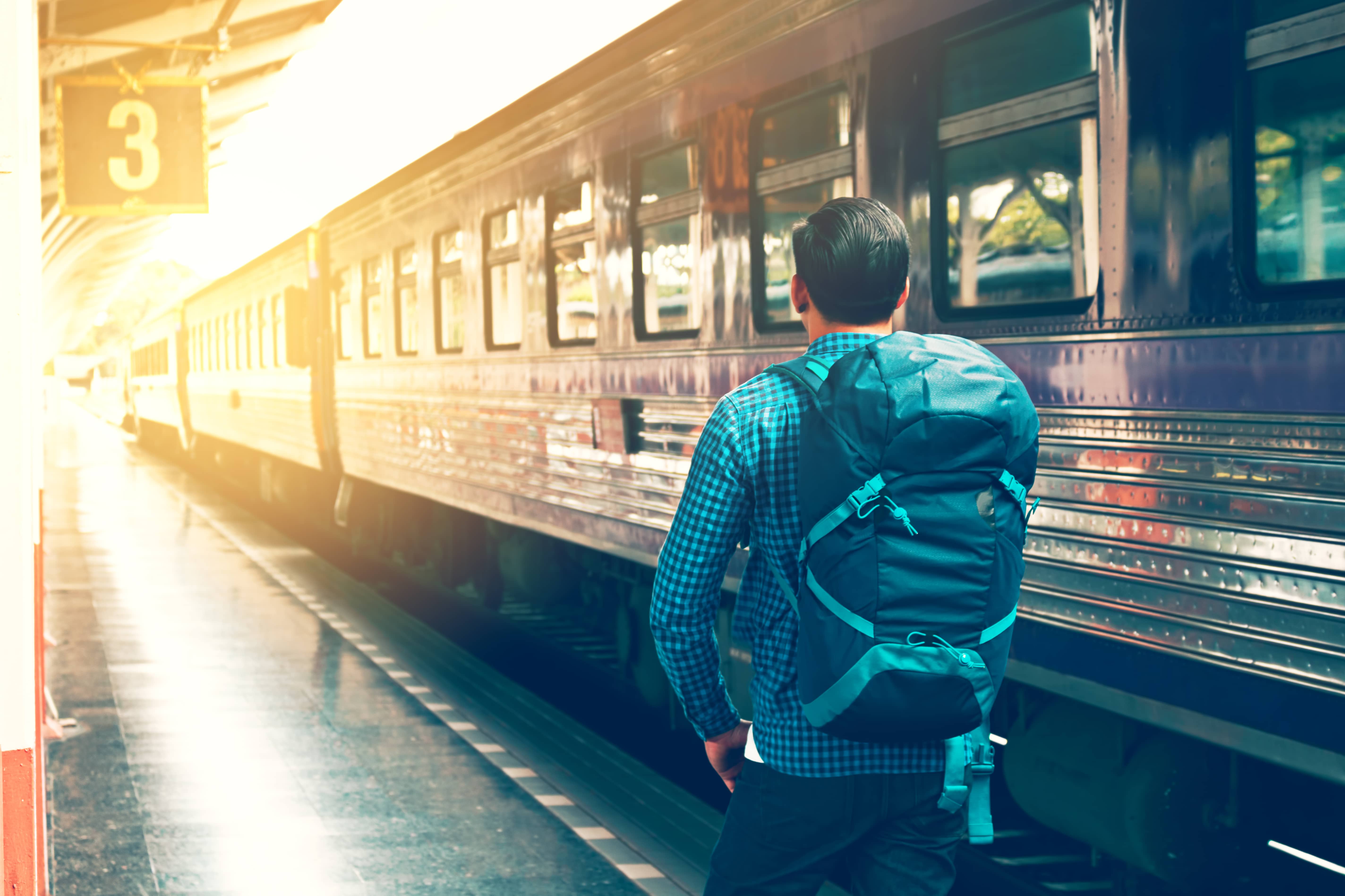 Train Spotting: A young man watches a train as it arrives at the train station at sunset.