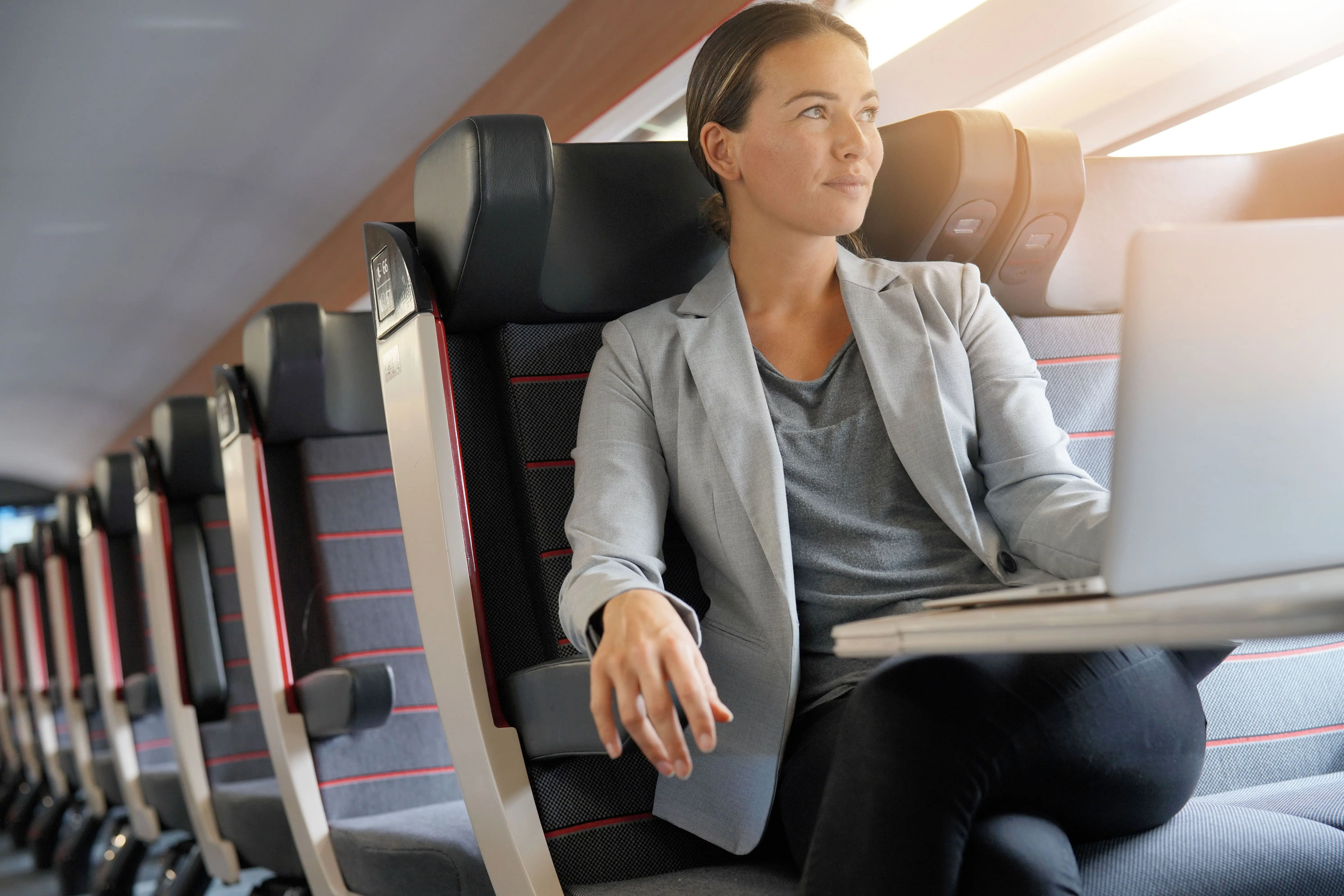 Why Travel on First Class Trains 2 First Class Train Tickets: A woman works on a laptop whilst relaxing in a First Class train seat.