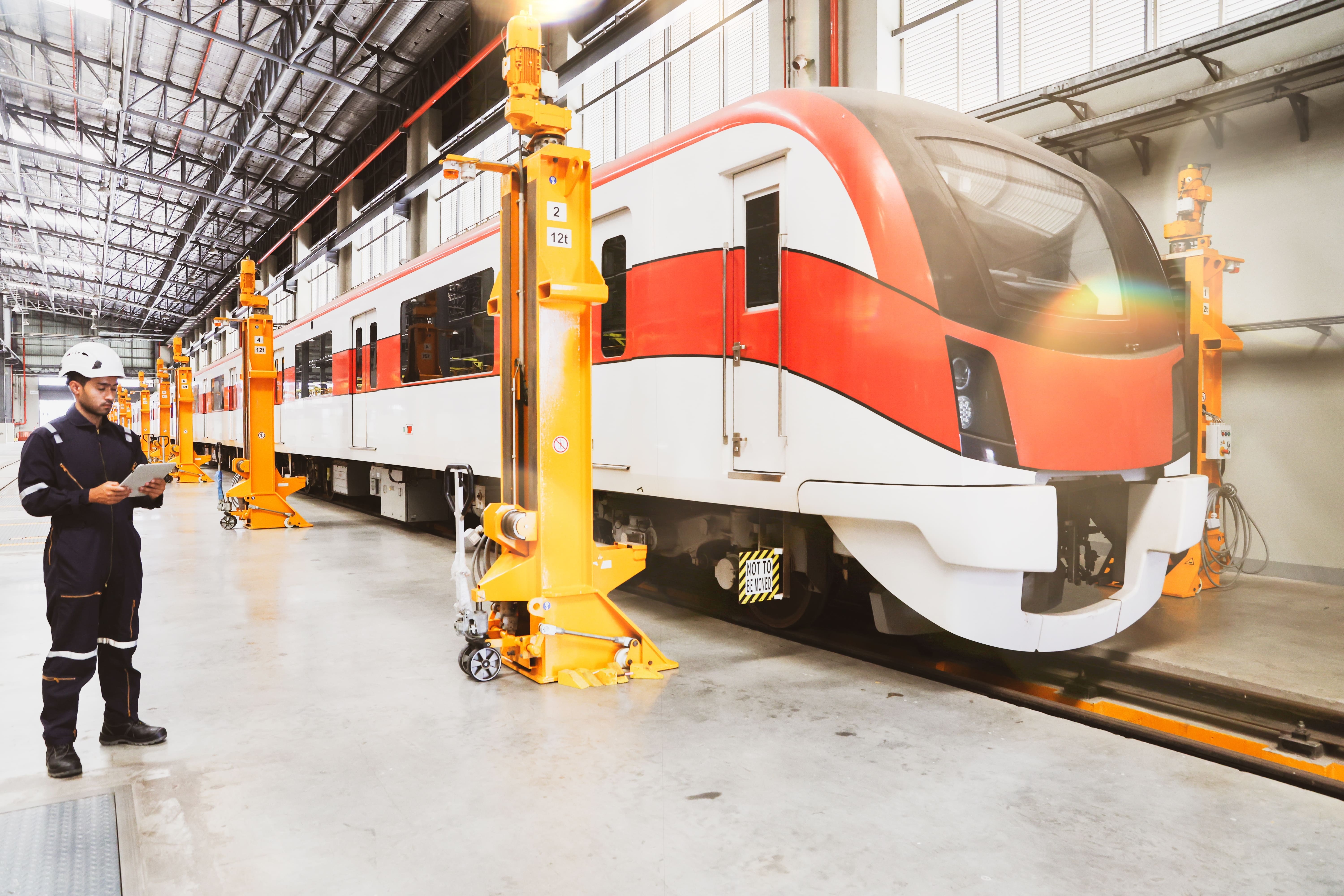 Future Trains: An engineer looks at a clipboard as they inspect a stationary electric train.