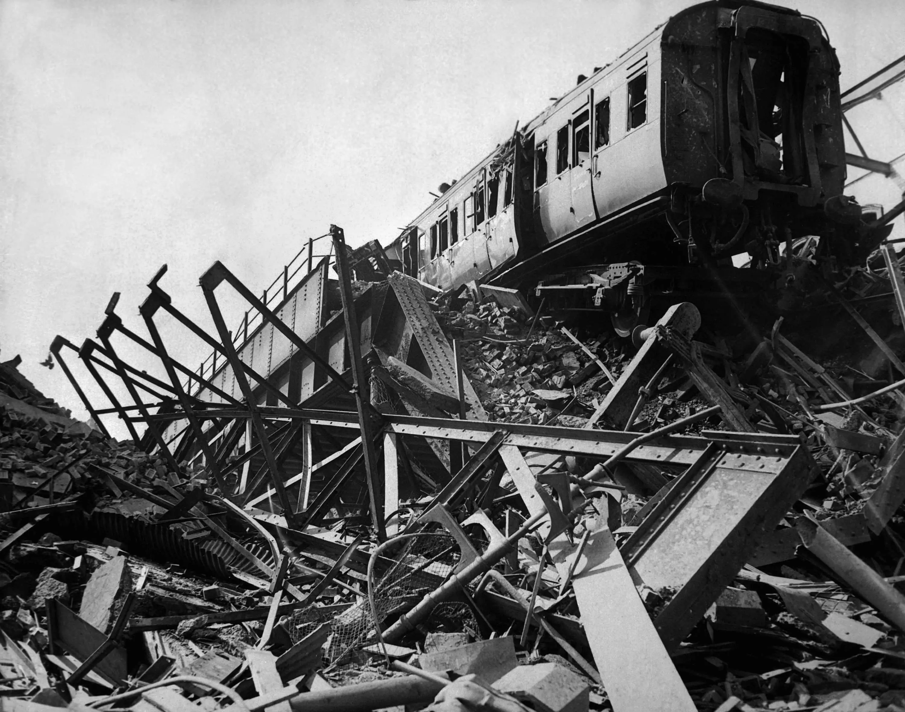 A black and white image of a train sat amongst a pile of rubble and destroyed railway track
