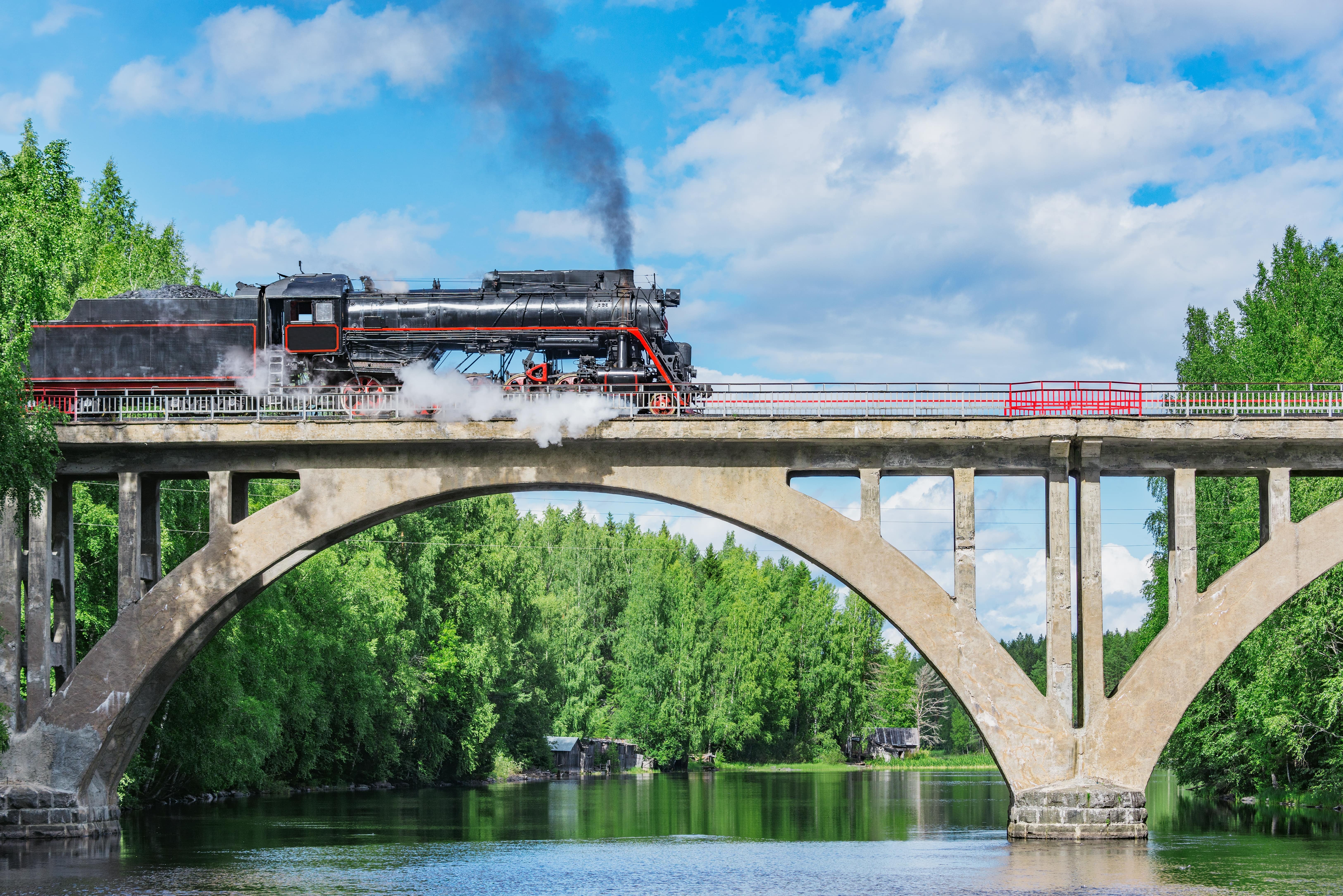 Steam Train Experiences: A stream train travels over a river.
