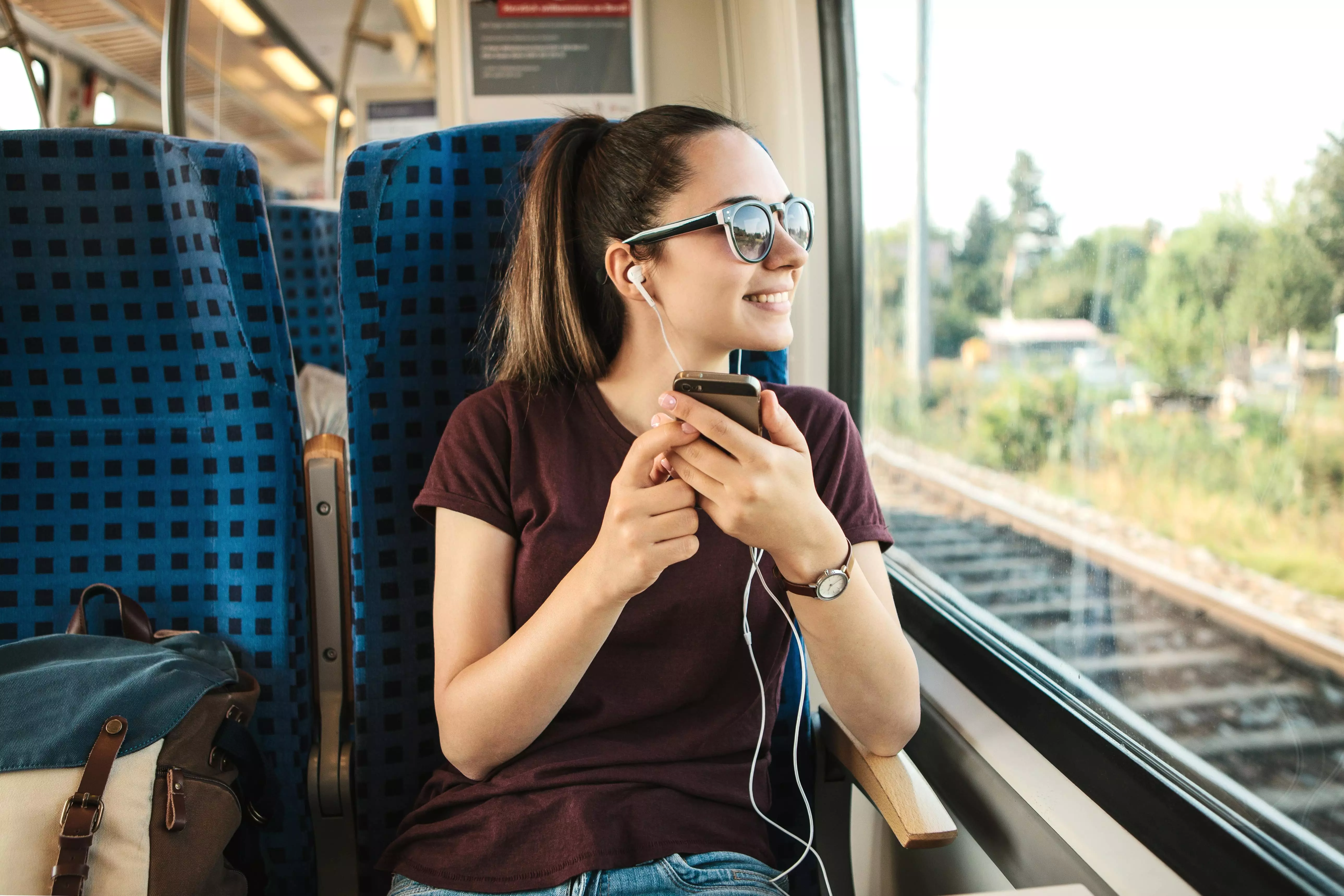 A young woman listens to music while traveling in a train.
